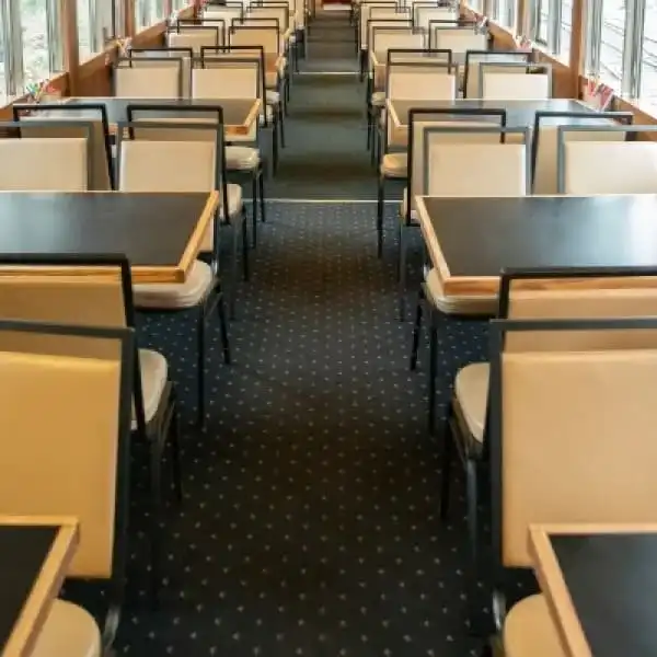 Empty dining area with rows of tables and chairs on a carpeted floor.